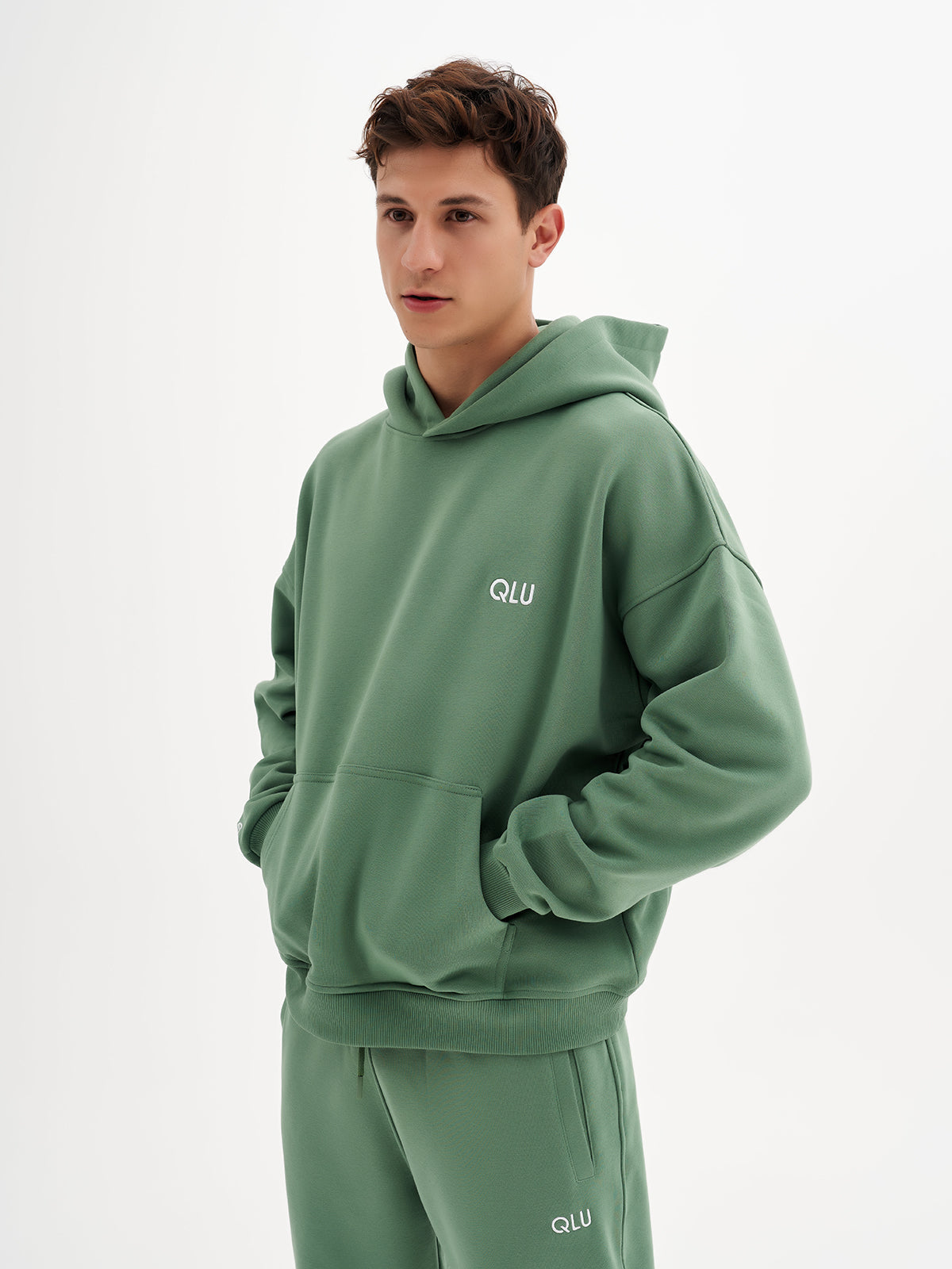 a young man wearing a green hoodie and sweatpants