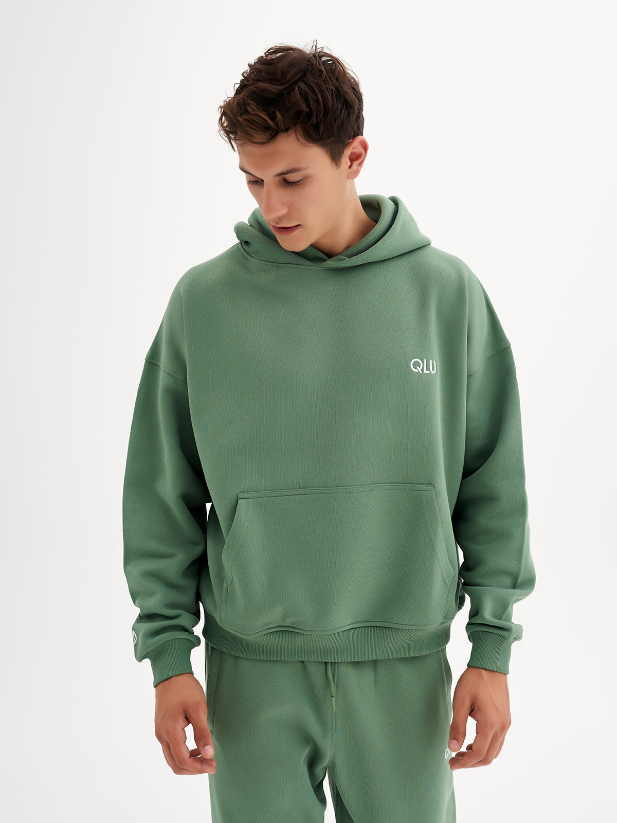 a young man wearing a green sweatshirt and sweatpants