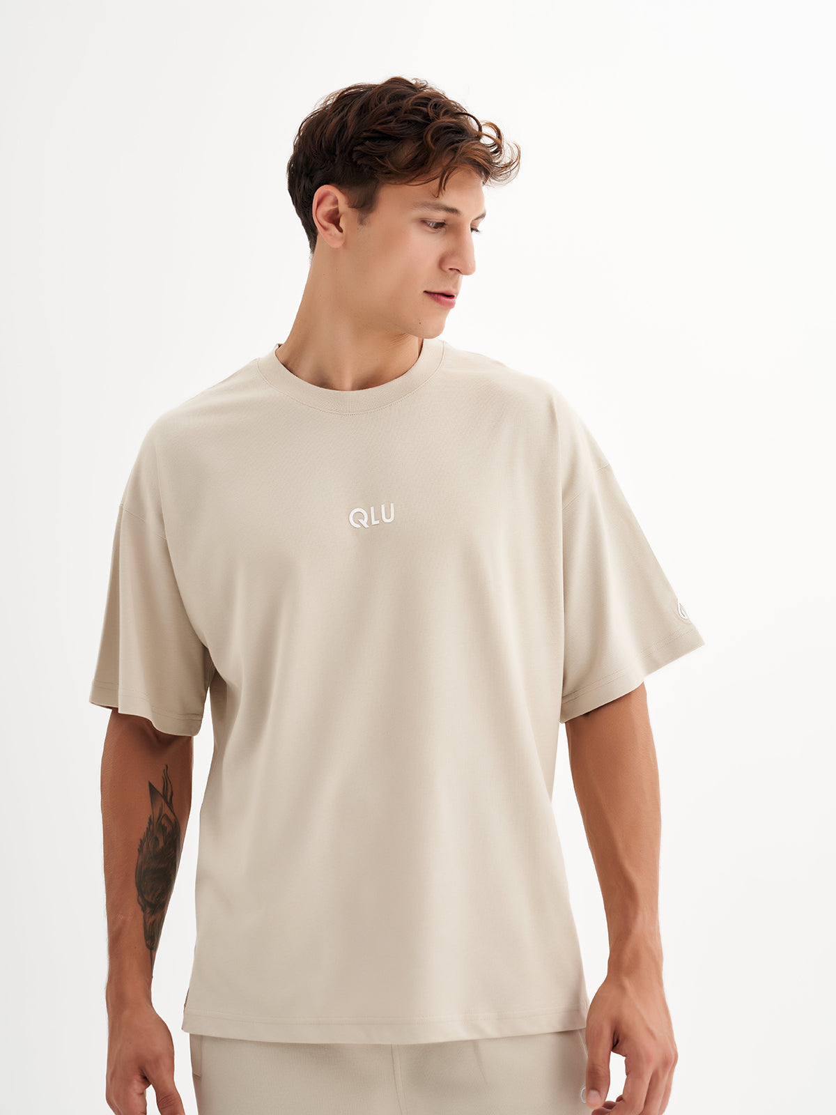 a man wearing a beige t - shirt with the word u on it