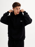 a young man in a black hoodie poses for a picture