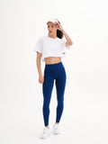 a woman in a white crop top and blue leggings