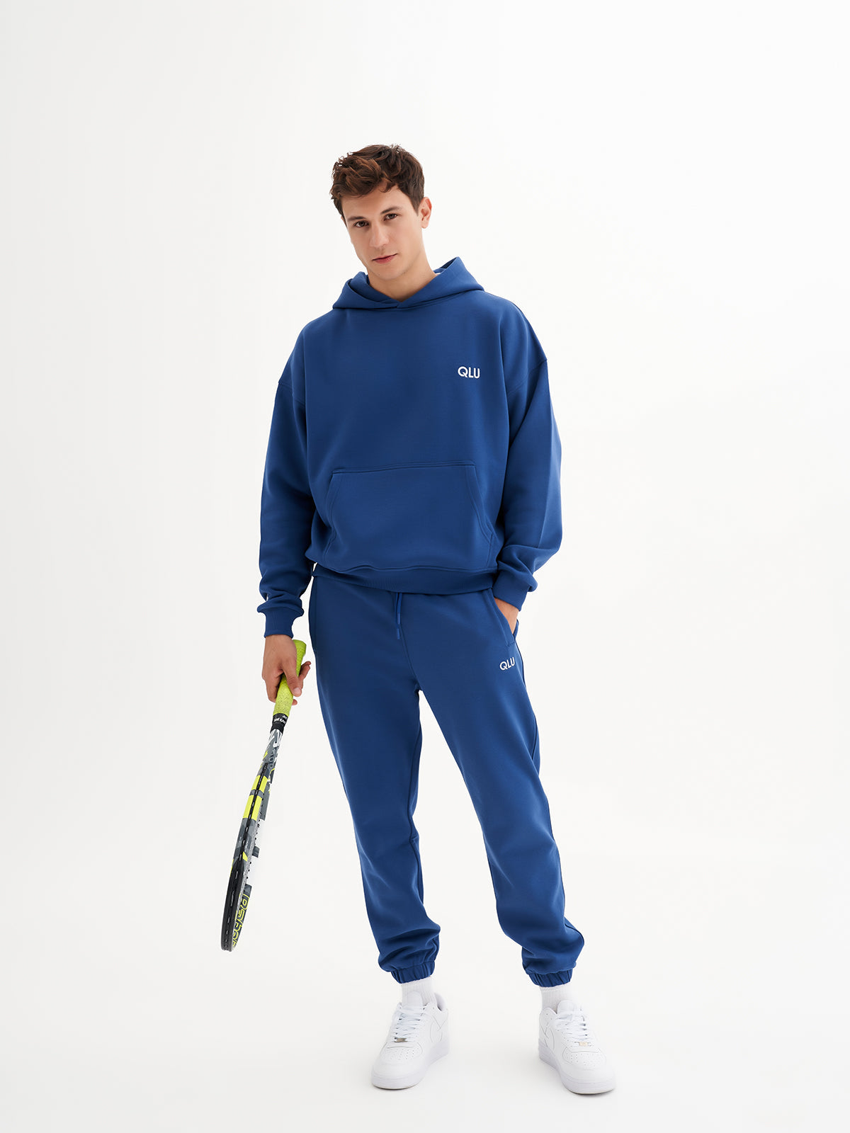 a man in a blue hoodie holding a tennis racket