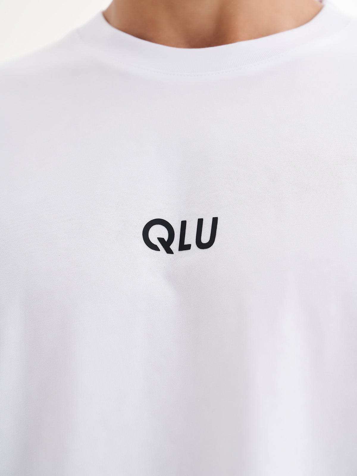 a man wearing a white t - shirt with the word qlu printed on it