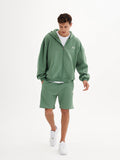 a man in a green hoodie and shorts