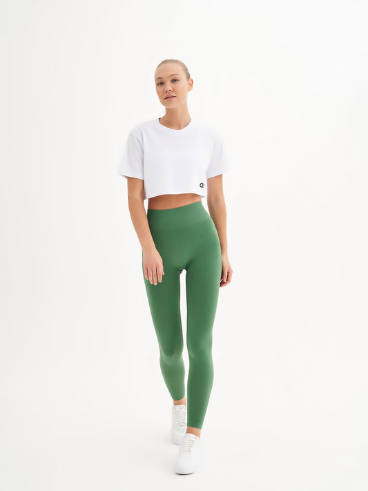 a woman in a white crop top and green leggings