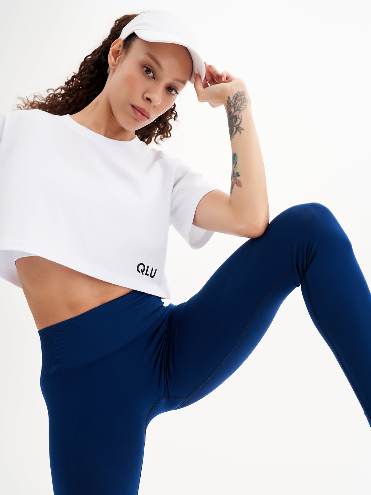 a woman in a white crop top and blue leggings