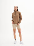 a woman wearing a brown sweatshirt and shorts