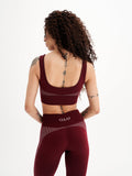 a woman in a maroon sports bra top and leggings