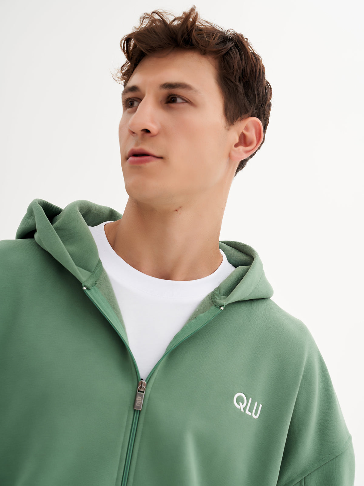 a young man in a green hoodie looking off to the side