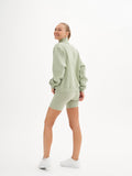 a woman in a green sweatshirt and shorts