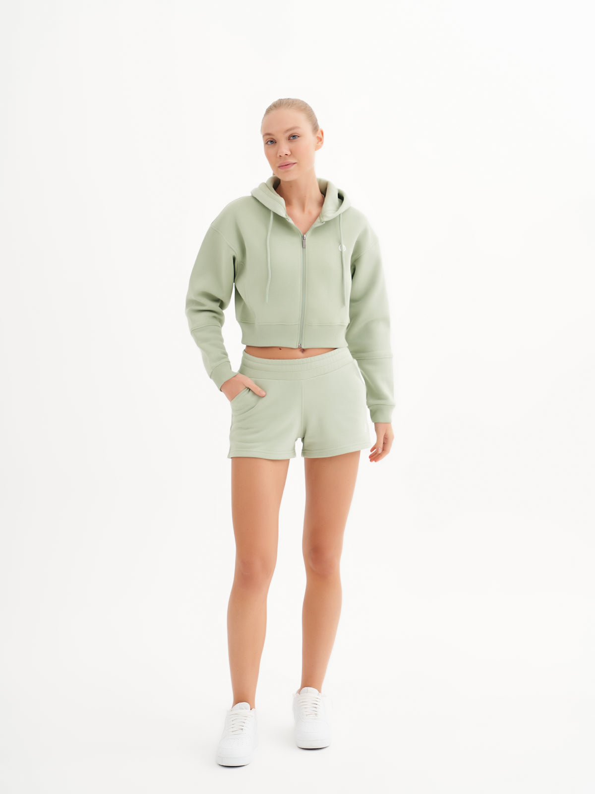 a woman in a light green sweatshirt and shorts