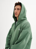 a young man in a green hoodie poses for a picture