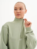 a woman in a light green sweatshirt poses for the camera