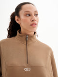 a woman wearing a tan top with a zipper