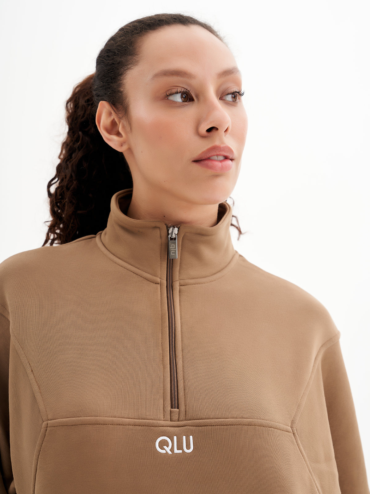 a woman wearing a tan top with a zipper