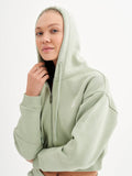 a woman in a green hoodie poses for a picture