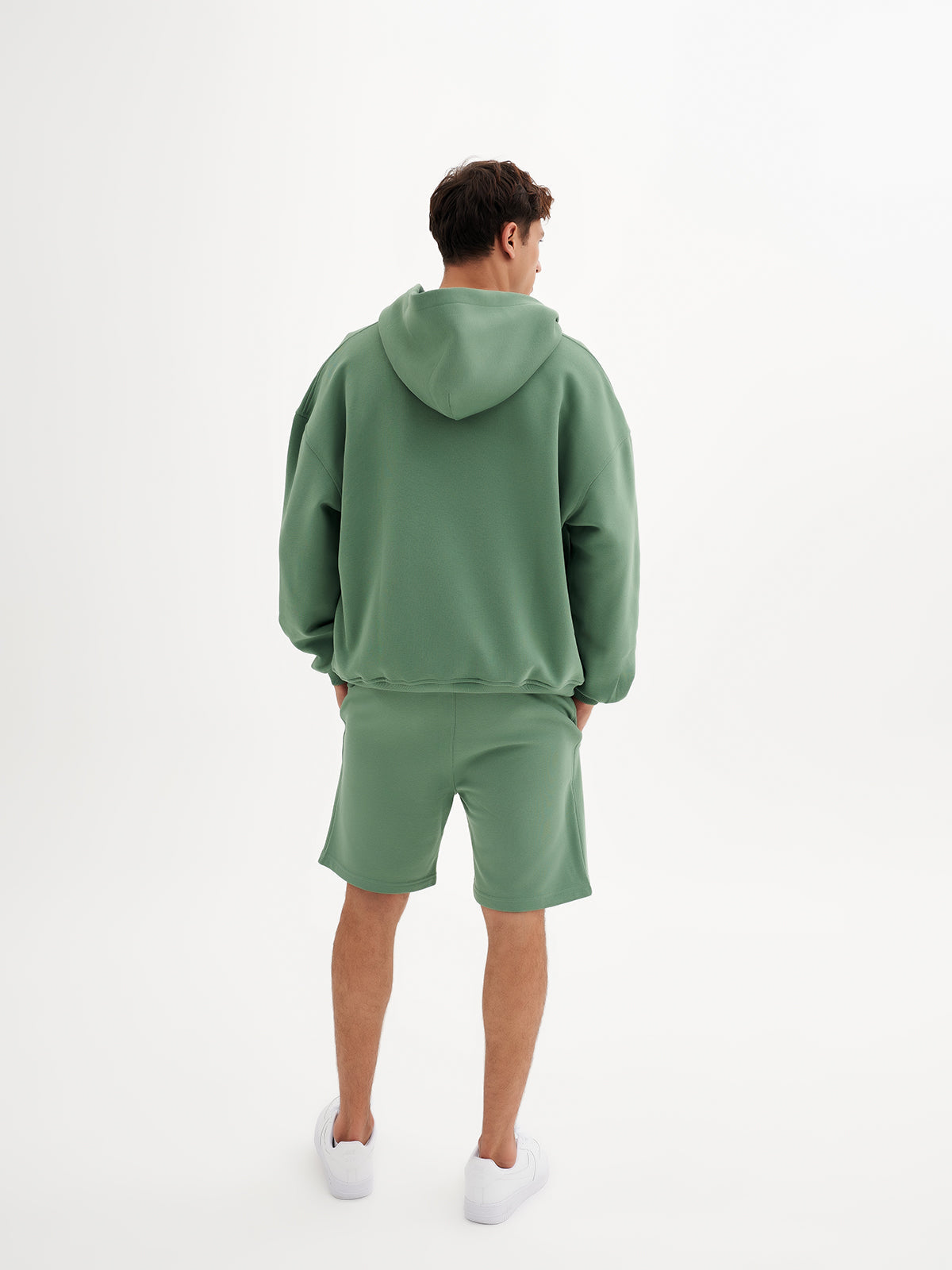 a man in a green sweatshirt and shorts