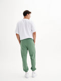 a man in a white shirt and green pants