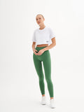 a woman in a white crop top and green leggings