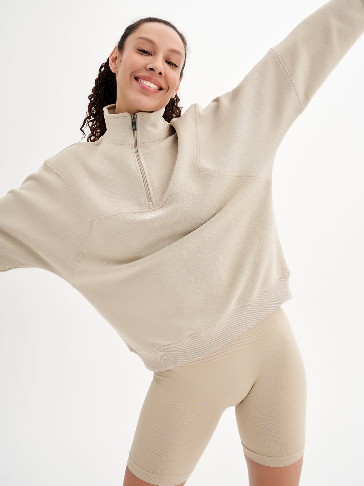 a woman in a beige sweatshirt and shorts