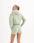 a woman in a light green sweatshirt and shorts