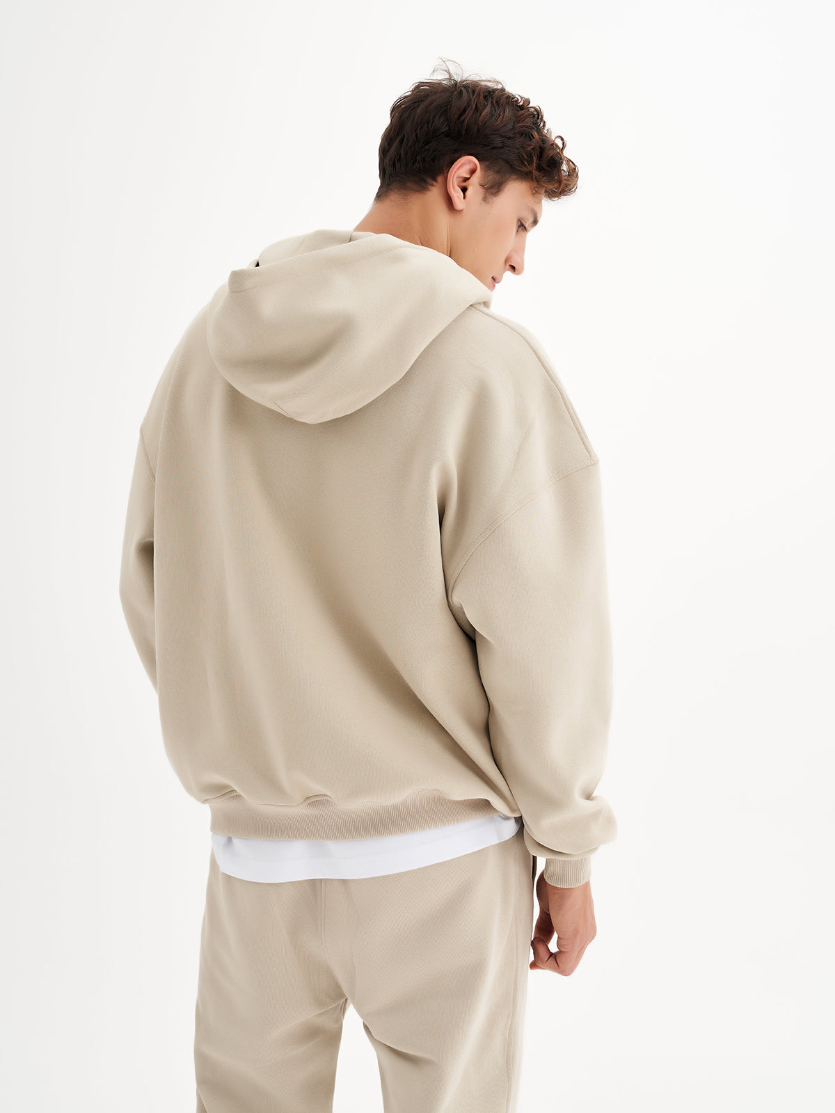 a man in a beige hoodie is facing away from the camera