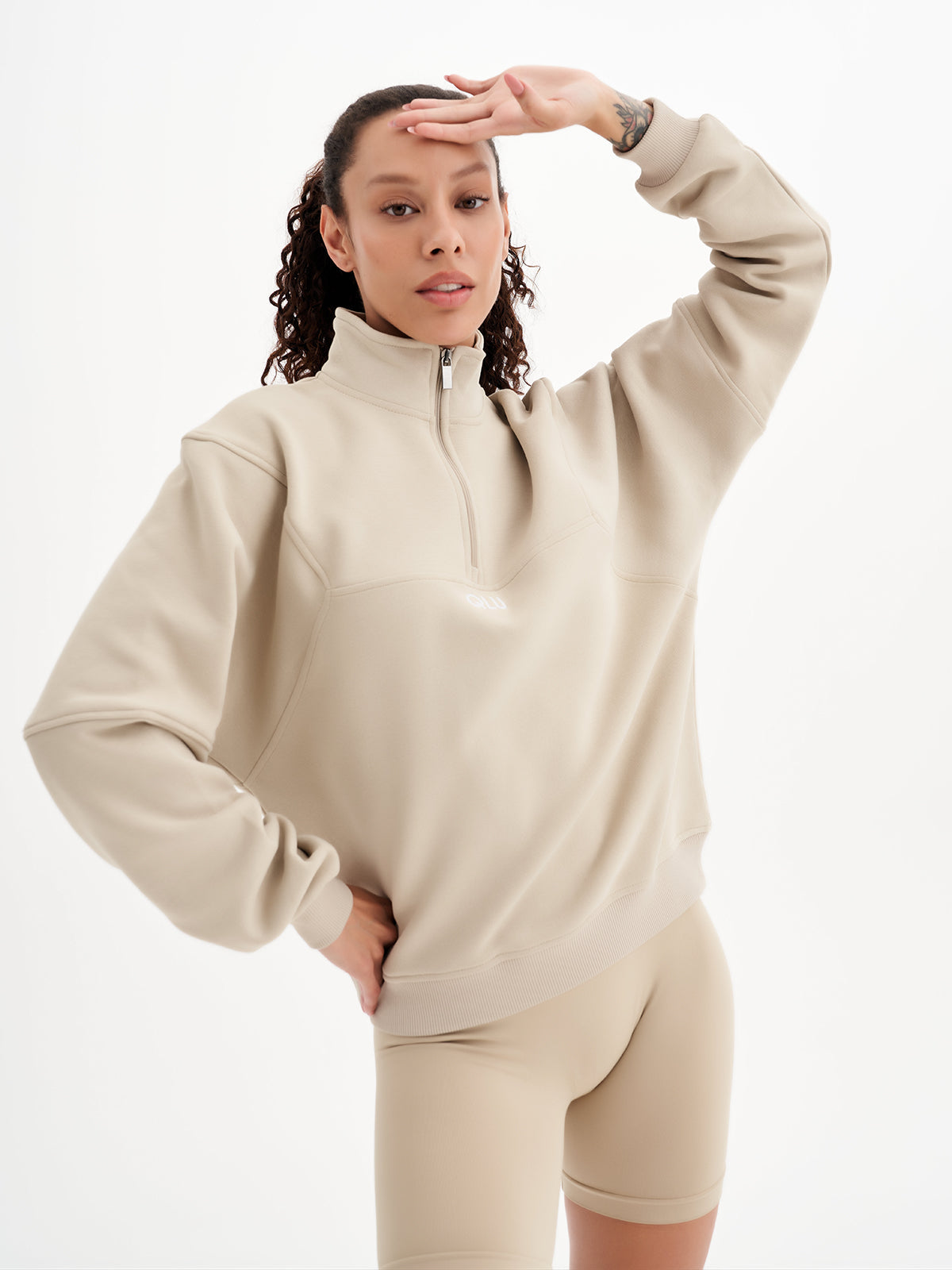 a woman wearing a beige sweatshirt and shorts