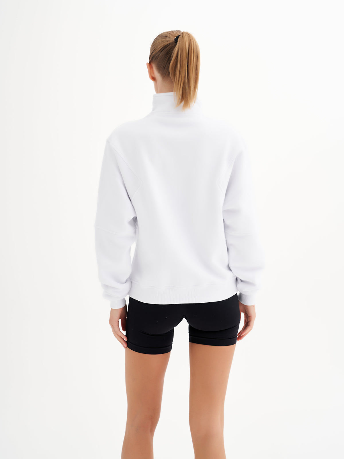 a woman wearing a white sweatshirt and black shorts