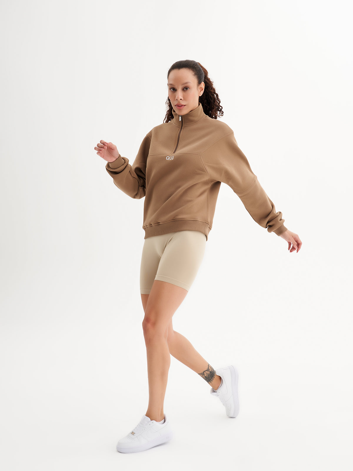 a woman in a brown sweatshirt and beige shorts