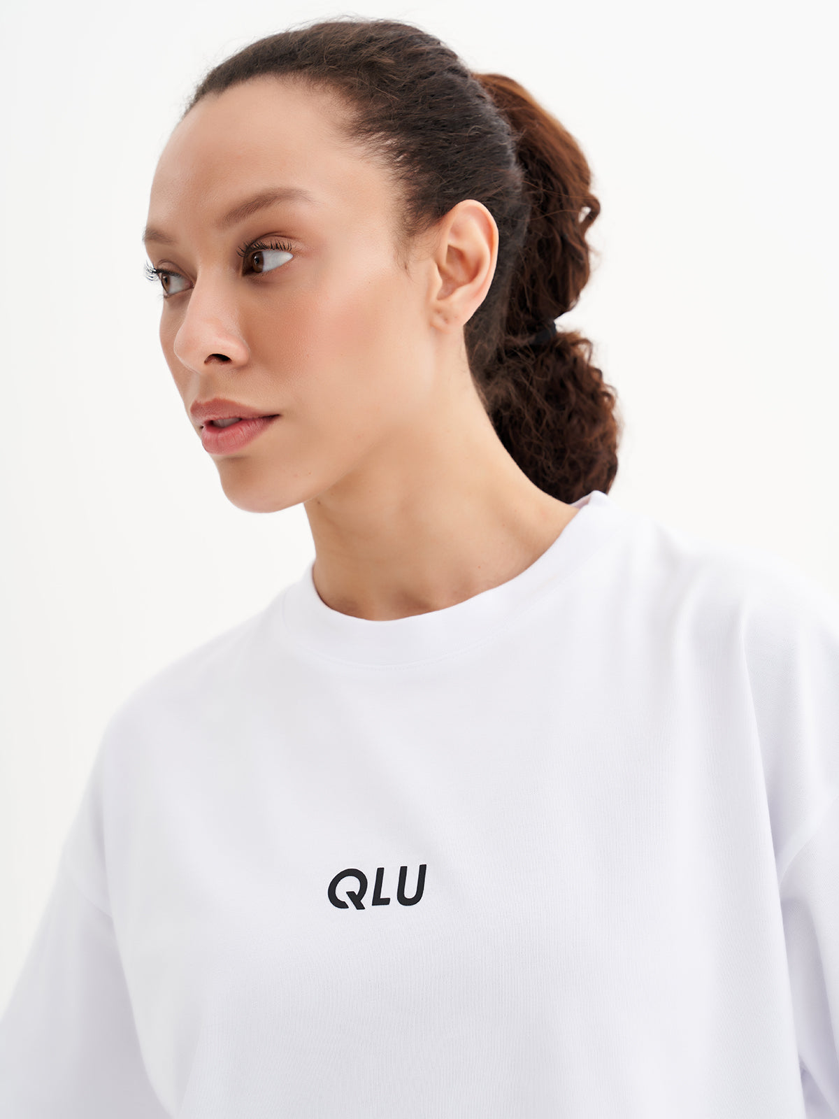 a woman wearing a white t - shirt with the word qui on it