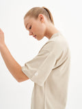 a woman in a beige shirt is holding a cell phone