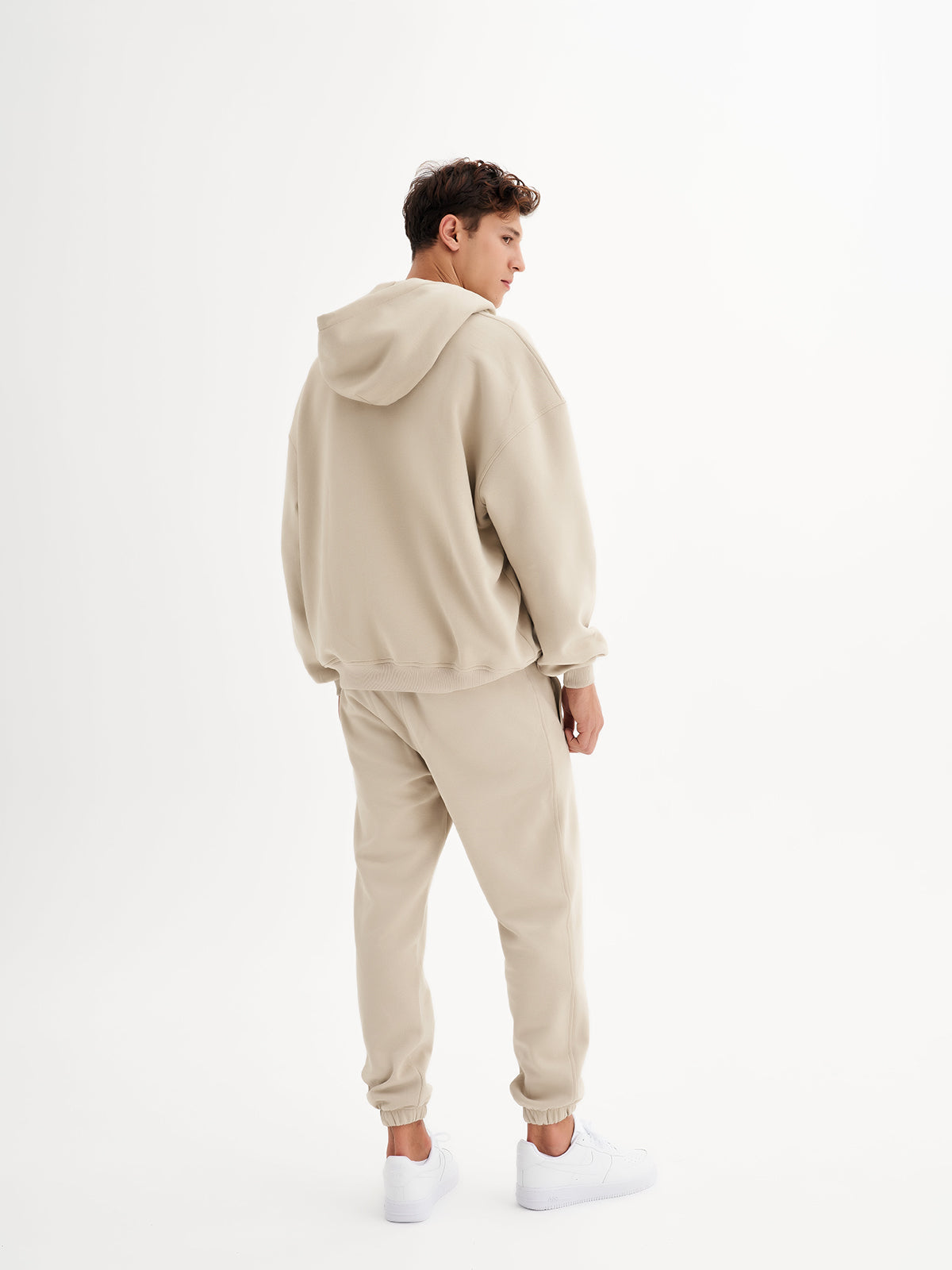 a man in a beige sweatshirt and sweat pants