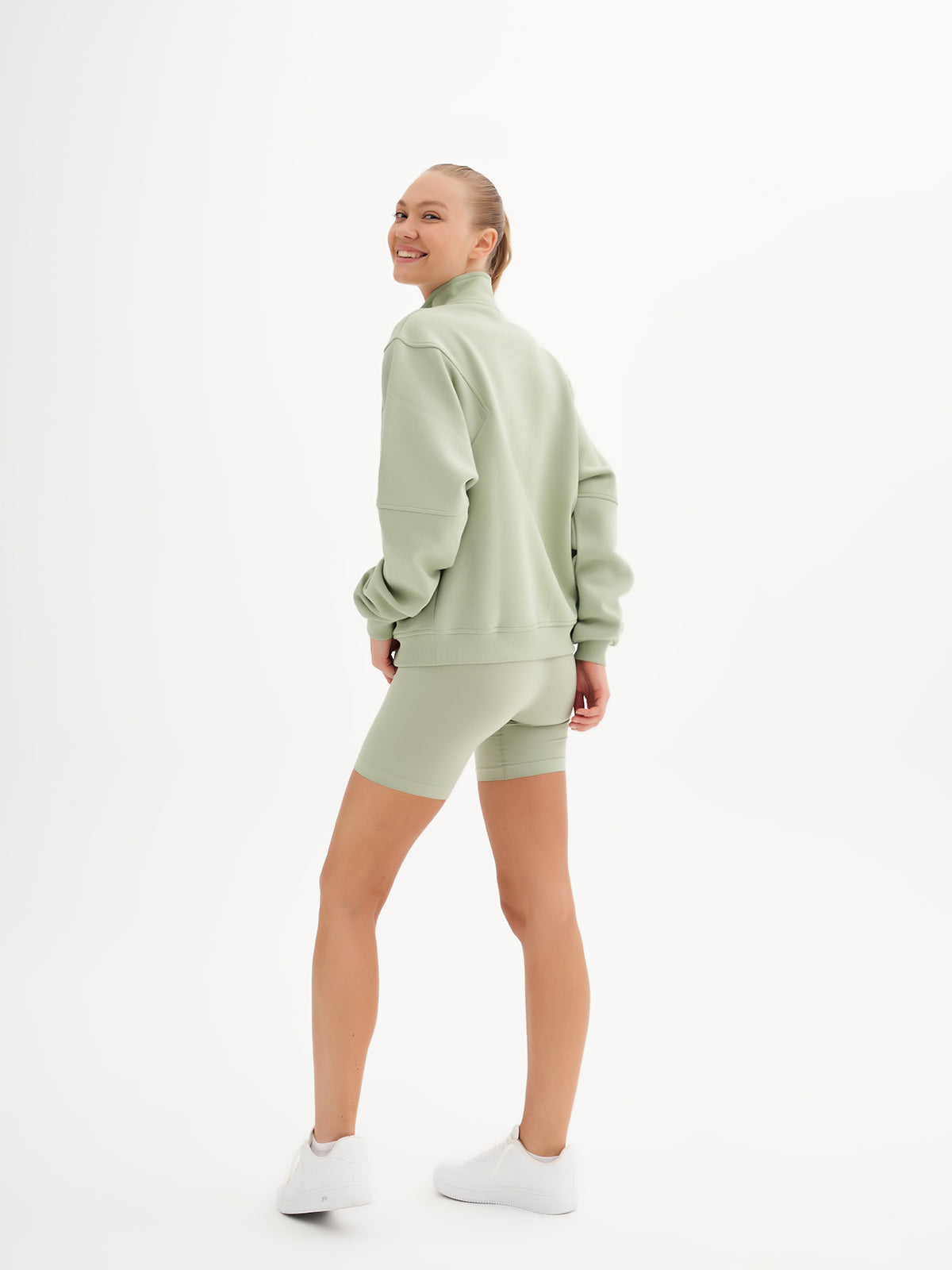 a woman in a green sweatshirt and shorts