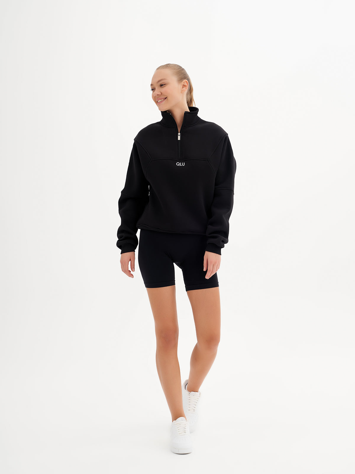 a woman in a black sweatshirt and shorts