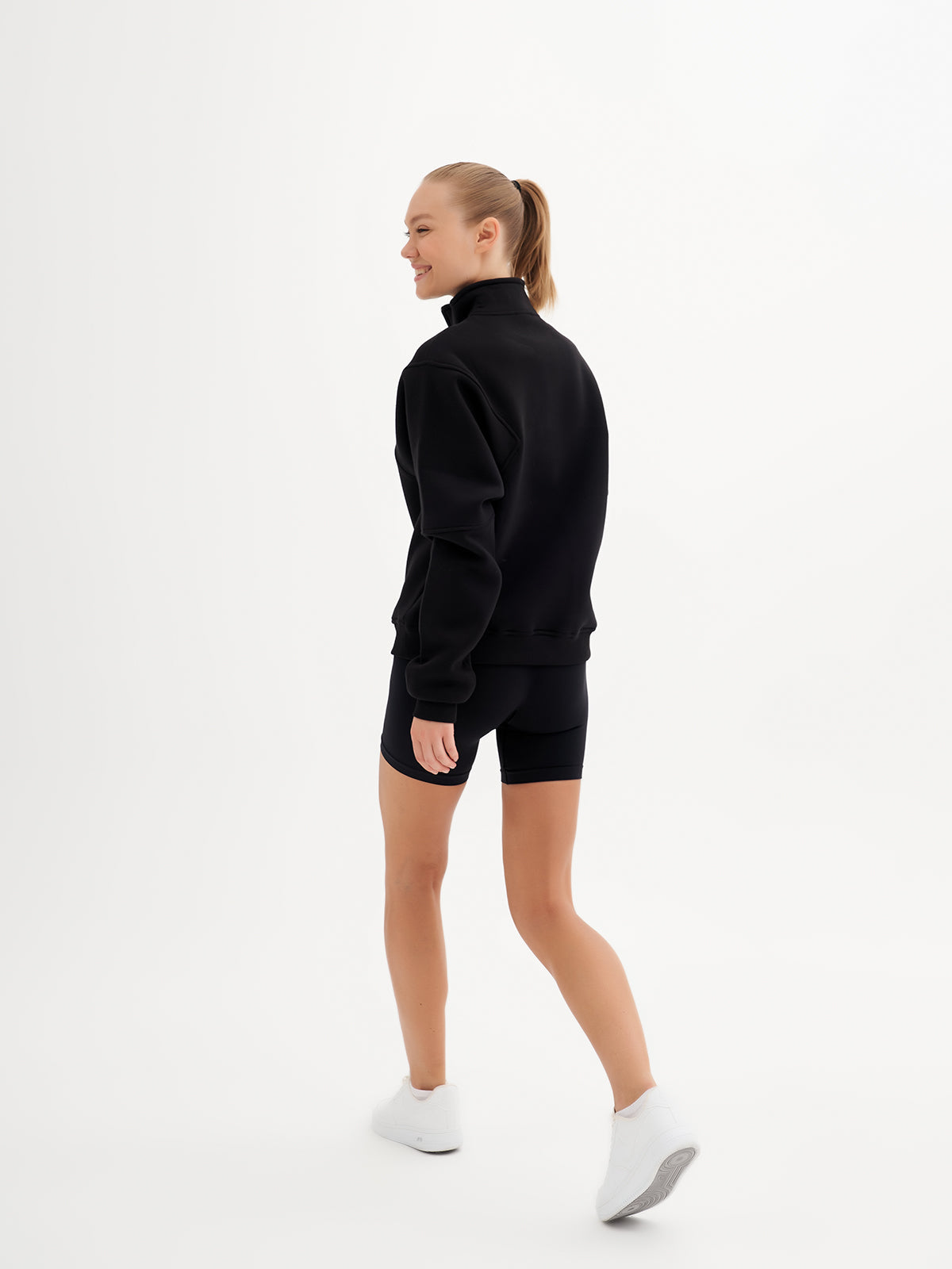 a woman in a black sweatshirt and shorts