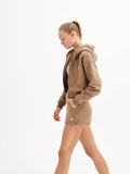 a woman in a brown hoodie is walking